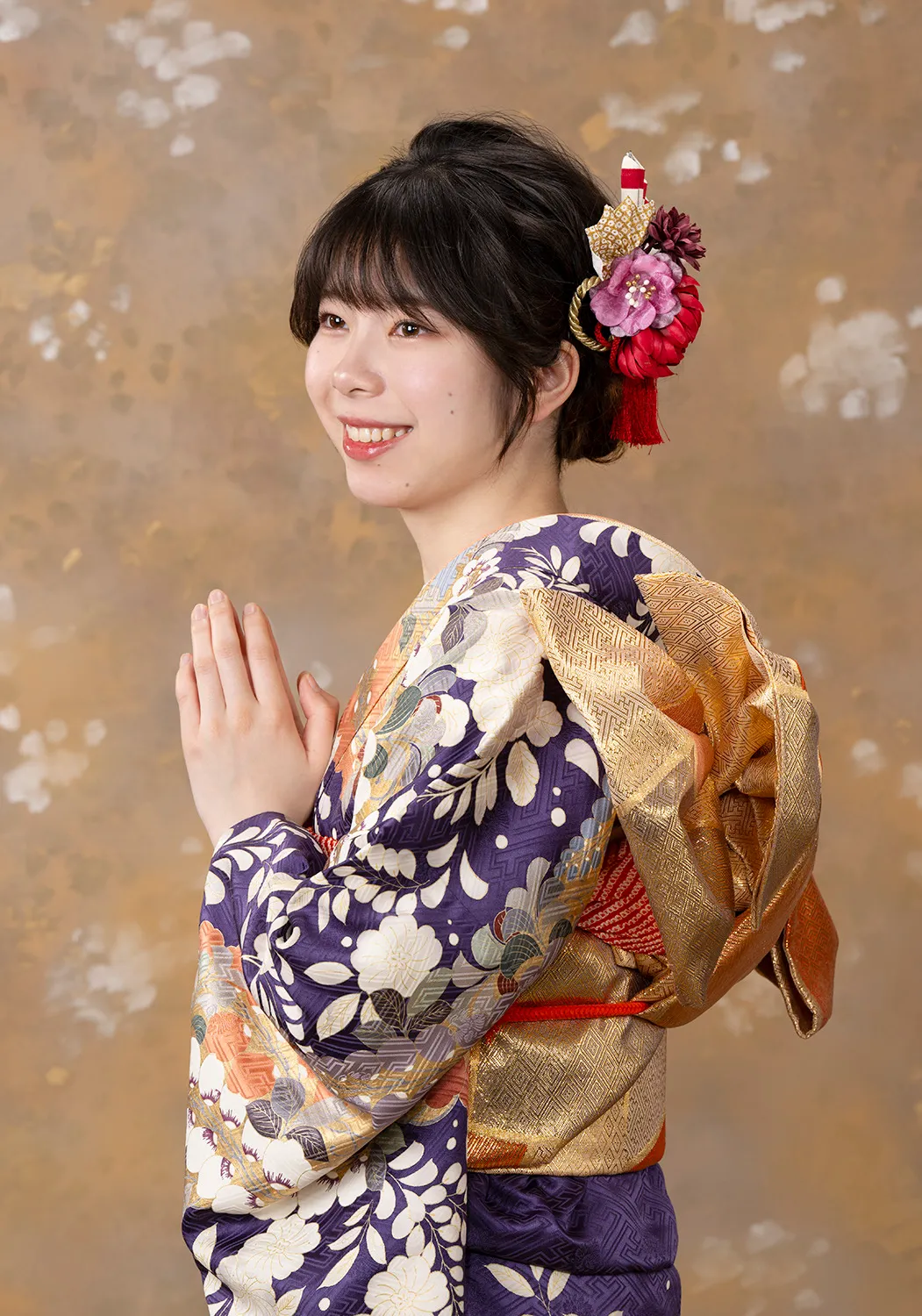 A woman wearing a navy and gold floral kimono with a decorative hair ornament.