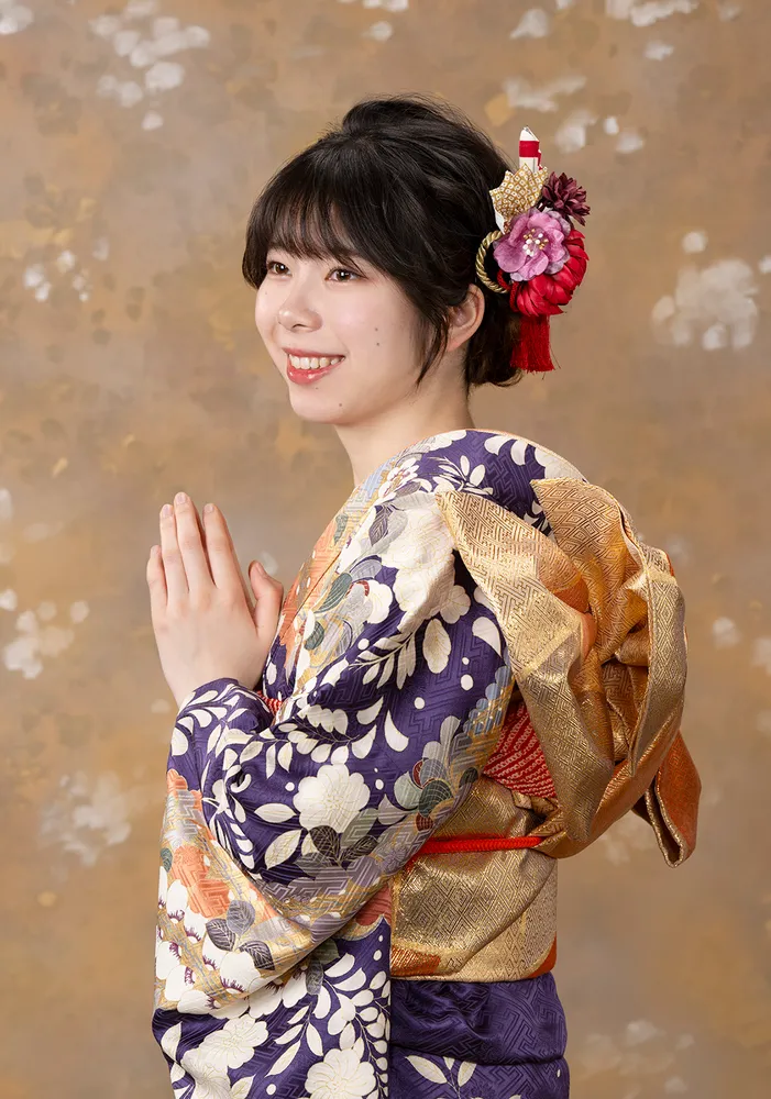 A woman wearing a navy and gold floral kimono with a decorative hair ornament.