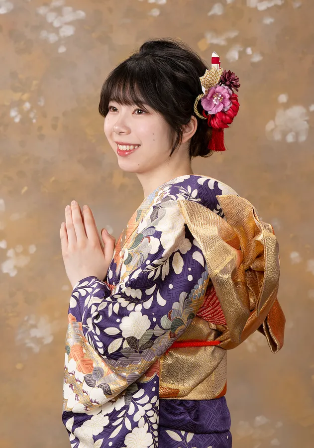 A woman wearing a navy and gold floral kimono with a decorative hair ornament.