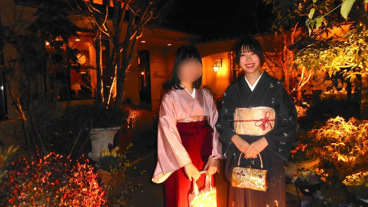 Two people wearing kimono at a nighttime garden event; one person's face is blurred for privacy.
