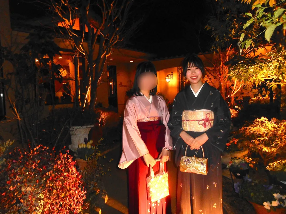Two people wearing kimono at a nighttime garden event; one person's face is blurred for privacy.